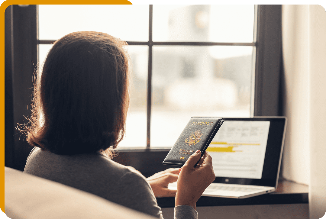 Person holding passport near laptop